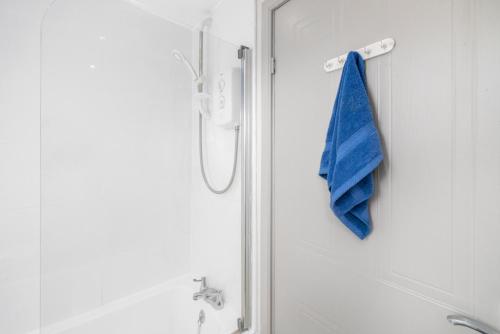 a blue towel is hanging on the door of a shower at I'm Your Host - Bridgeton House in Glasgow