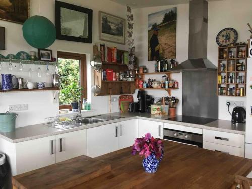 a kitchen with white cabinets and a vase of flowers at Spacious cabin on isolated farm with sea view in Bude