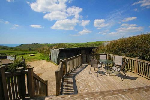 a wooden deck with a table and chairs on it at Spacious cabin on isolated farm with sea view in Bude