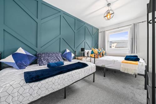 a bedroom with two beds and a blue wall at I'm Your Host - Bridgeton House in Glasgow