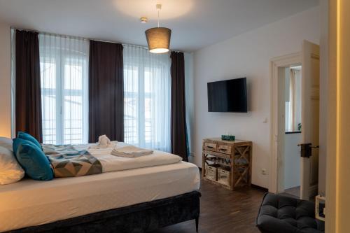 レーゲンスブルクにあるLiboria: Stylische Altstadtwohnungのベッドルーム(ベッド1台、テレビ、椅子付)