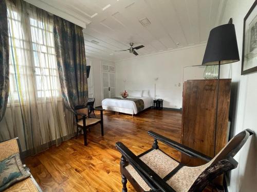 ein Zimmer mit einem Bett und einem Stuhl darin in der Unterkunft Villa Angélique - Hôtel classé Monument Historique in Saint-Denis