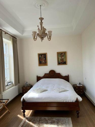 a bedroom with a large bed with a chandelier at De Pastory in Grote-Brogel