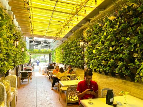 un homme assis à une table dans un restaurant avec des plantes dans l'établissement Capsule Riverside, à Hô-Chi-Minh-Ville