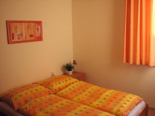 a bed with an orange comforter in a bedroom at Apartmán Oščadnica in Oščadnica