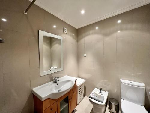 a bathroom with a sink and a toilet and a mirror at Albufeira Garden Villa With Pool by Homing in Albufeira