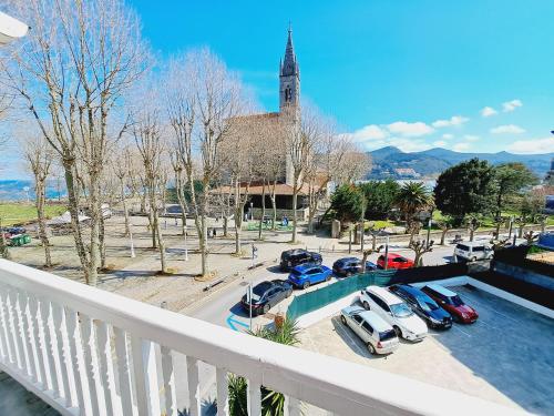 a balcony with cars parked in a parking lot with a church at Hotel Atalaya- FREE PARKING GRATUITO in Mundaka