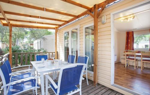 un comedor con sillas azules y una mesa en una terraza en MobileHome 8 Personnes avec Clim situé au Camping l'Elysée Grau du roi Vagues Océanes By CapFun en Le Grau-du-Roi