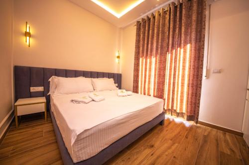 1 dormitorio con 1 cama con sábanas blancas y ventana en Hotel Vila Misiri, en Durrës