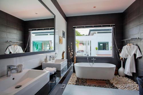 a bathroom with a tub and a sink and a mirror at Sumptuous Modern 3BR Pool Villa Mandala in Ban Saiyuan (1)