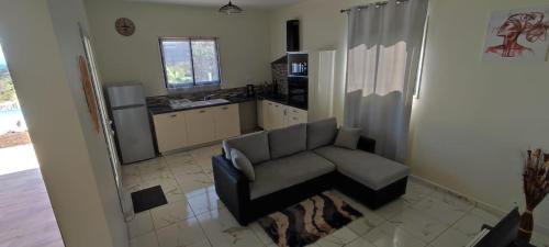 a living room with a couch and a kitchen at ALLAMANDA DES BOIS in Deshaies