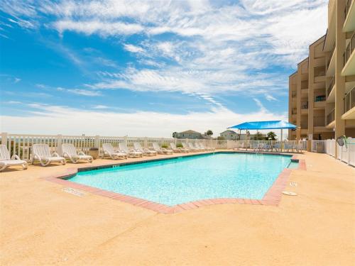 a swimming pool with lounge chairs and an umbrella at Laguna Reef #306 - Capm Kens in Rockport