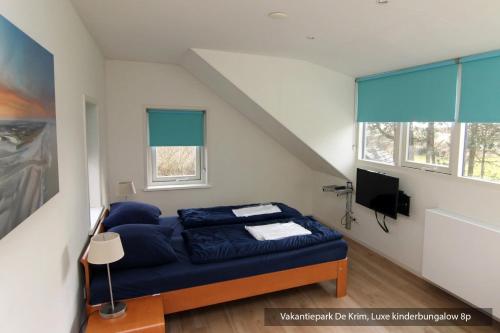 a bedroom with a blue couch in a room with windows at Vakantiepark De Krim Texel in De Cocksdorp