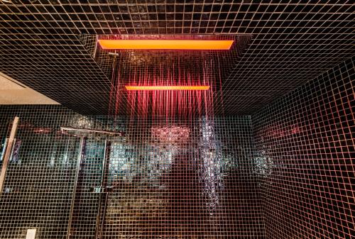 a bathroom with a glass shower with a red light at Olux Hotel-Motel-Suites in Laval