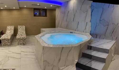 a large tub in a room with a stone wall at Belvedere Zlatibor LUX & SPA Apartment in Zlatibor