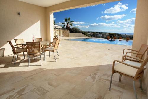 a patio with a table and chairs and a pool at Seafront 5 Bedroom Villa Paradise in Sea Caves in Peyia