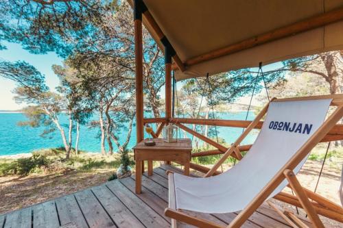uma cadeira de balanço num deque com o oceano ao fundo em Obonjan Island Resort em Šibenik