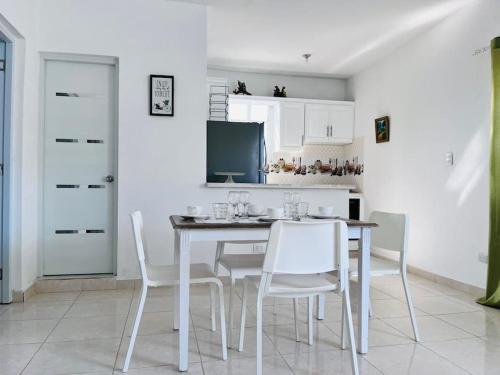 a dining room with a table and white chairs at Complejo girasol in Santo Domingo