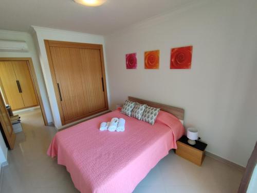 een slaapkamer met een roze bed en 2 witte handdoeken. bij 1D Areias de Porches, Pool & A/C - Casas & Papéis in Armação de Pêra