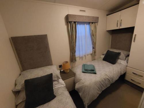 two beds in a small room with a window at Drumrammer Farm Lodge in Ahoghill