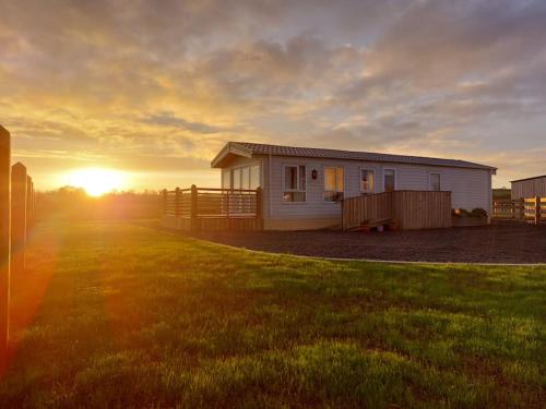 a small house in a field with the sunset in the background at Drumrammer Farm Lodge in Ahoghill