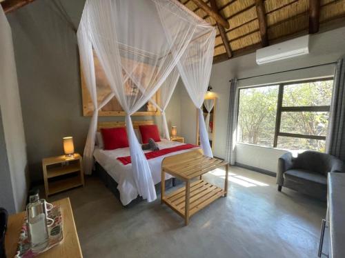 a bedroom with a canopy bed and a chair at Lindiwe Safari Lodge in Hoedspruit