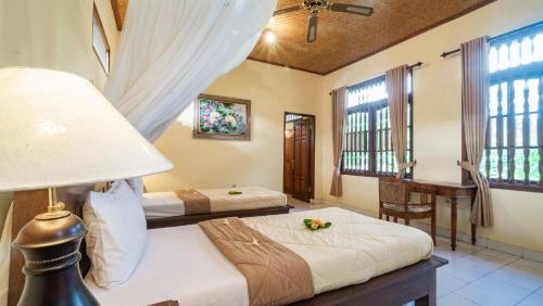 a bedroom with two beds and a lamp and windows at Cafe Wayan Cottages Senggigi in Senggigi 