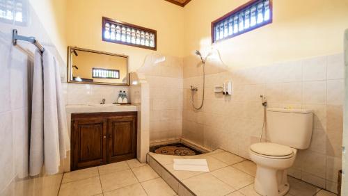y baño con aseo y lavamanos. en Cafe Wayan Cottages Senggigi, en Senggigi 