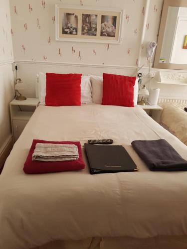 a bed with red pillows and a laptop on it at The Brema Hotel in Blackpool