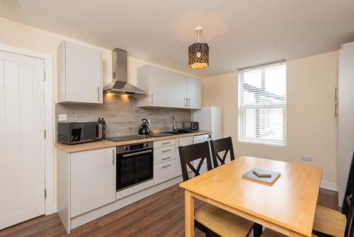 a kitchen with white cabinets and a wooden table with chairs at Number 46 in Langley Park