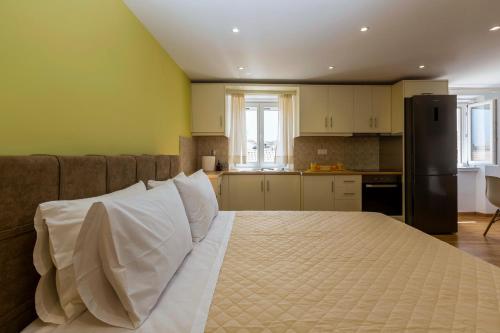 1 dormitorio con 1 cama grande con almohadas blancas en Sunny Morning at Saint Spyridon by CorfuEscapes, en Corfú