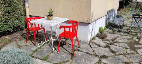 two red chairs and a white table with a plant on it at Les Colibris - Standing et Jardin - 3 étoiles in Cluses