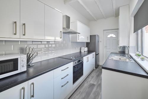 a white kitchen with white cabinets and a sink at Host & Stay - North Seaton Road in Newbiggin-by-the-Sea