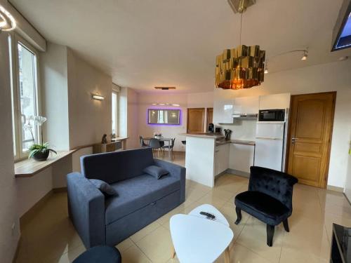 ein Wohnzimmer mit einer blauen Couch und einer Küche in der Unterkunft Résidence Investar appartement 1 in Montluçon