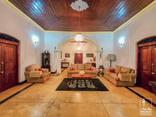 a living room with couches and a wooden ceiling at Kithulvilla Holiday Bungalow in Kitulgala