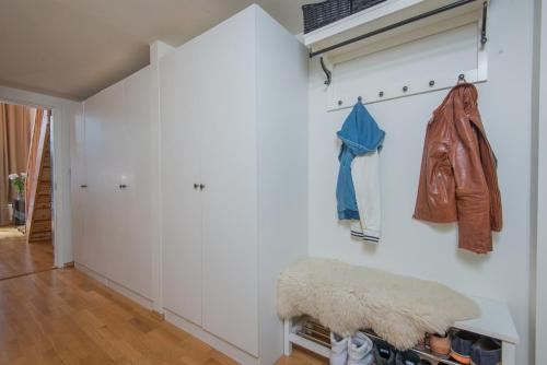 a hallway with a white wall with a bench and coats at Super central - Unique studio apartment - 4 people in Oslo