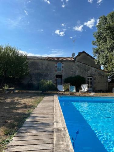 une piscine avec deux chaises et une maison dans l'établissement La laiterie, à Bouhet