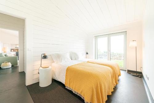 a white bedroom with a bed with a yellow blanket at Casas da Prainha A in Prainha de Baixo