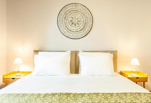 a bedroom with a bed with white sheets and two lamps at Mandorla Apartments in Rhodes Town