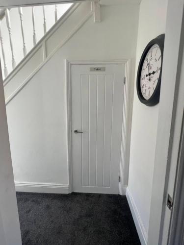 a hallway with a door and a clock on the wall at Beck View House in Stockton-on-Tees
