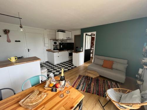 a kitchen and living room with a table and a couch at LA MADELEINE DES GRANDS SABLES 1- 4 PERS in Le Pouldu
