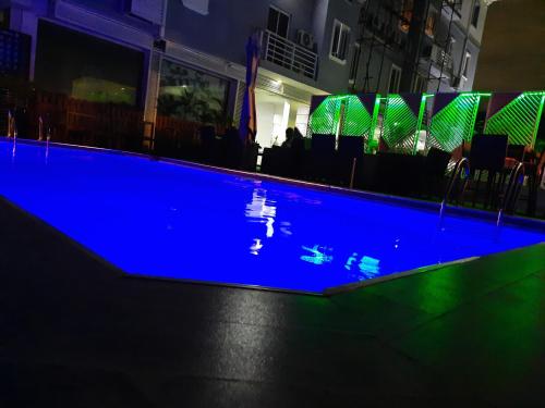 una piscina por la noche con iluminación azul en James Court Hotel & Luxury Apartments, en Lekki