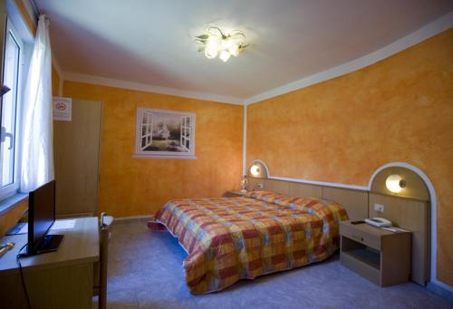 a bedroom with a bed and a desk and a window at Albergo Ristorante Turchino in Campo Ligure