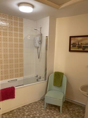 a bathroom with a bath tub and a green chair at Charming Pretty cottage in Banbury