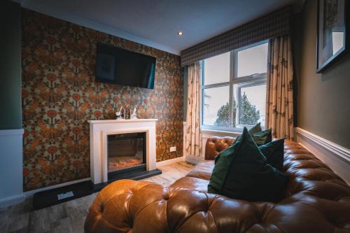 a living room with a leather couch and a fireplace at The Inn At Grasmere in Grasmere
