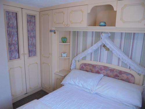 a bedroom with a white bed with a canopy at 5 Berth on Coral Beach (Granada) in Ingoldmells
