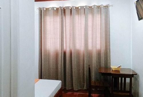 um quarto com uma janela com cortinas e uma secretária em RedDoorz @ Reana Seaside Pensione House Guindulman em Guindulman