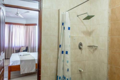 1 dormitorio con 1 cama y baño con ducha. en Ikhaya serviced Apartments With Sea View, Nyali, en Mombasa