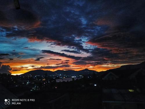a sunset in the sky with a city and mountains at Mount Elegance in Nuwara Eliya