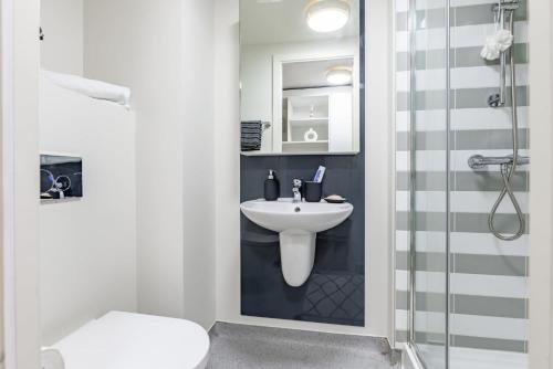 La salle de bains blanche est pourvue d'un lavabo et d'une douche. dans l'établissement For Student Only Classic Studio at The Glassworks near Newcastle City Centre, à Newcastle upon Tyne
